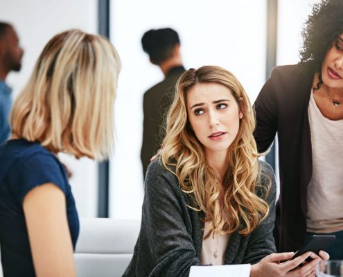 Three women in an office discuss a serious matter